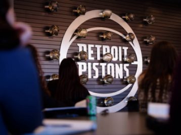 Detroit Pistons metal sign with clear basketballs with golden lines mounted on the wall in a grid around it.